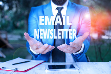 Text sign showing Email Newsletter. Business photo showcasing email sent out to inform the audience of the latest news Man with opened hands in fron of the table. Mobile phone and notes on the table