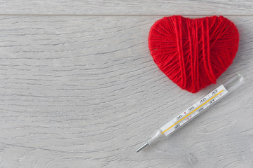 An old mercury thermometer with syringe and red heart on wood background. Medical health care.