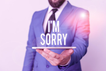 Conceptual hand writing showing I M Sorry. Concept meaning To ask for forgiveness to someone you unintensionaly hurt Businessman in blue suite with a tie holds lap top in hands