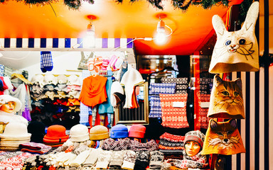 Sticker - Knitted goods displayed on a Christmas market stall. Old Town of Riga, Latvia. Wool mittens, gloves, socks with hats in winter. Street Xmas and holiday fair in European city. Advent Crafts on Bazaar