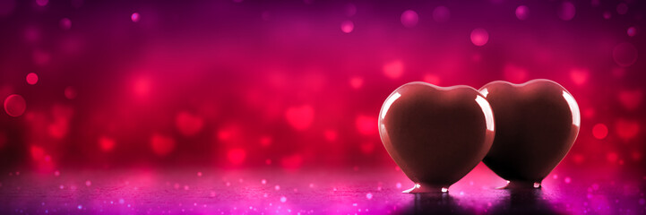 Wall Mural - banner of two hot melted chocolate hearts with soft heart shaped bokeh and romantic red background -