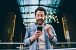 © BullRun - Emotional caucasian hipster guy excited with result of match victory watching video online on smartphone and 4G connection, happy millennial male overjoyed with get new free app for mobile phone .