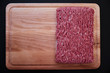 © Stanislav - Raw minced pork on wooden cutting board on black background close-up. top view, copy space left