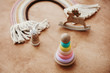 © sonyachny - Stylish wooden toys for child on wooden table. Modern colorful wooden pyramid with rings, wooden bunny and macrame rainbow. Eco friendly plastic free toys for toddler