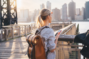 Wall Mural - Back view of international tourist with trendy backpack enjoying time for exploring USA megalopolis - New york standing at Brooklyn district and looking around at landscape of big city area