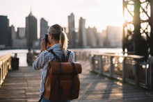 Back View Of Skilled Amateur Photographer Taking Pictures Of American City Enjoying Summer Trip To USA, Female Tourist With Trendy Rucksack Testing Modern Technology For Making View Photos