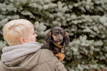 Woman hugging her dog on fir tree background outdoors