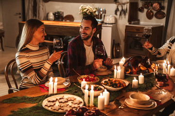 Photo of people drinking wine and smiling while having Christmas dinner