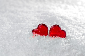 Two red hearts lie on the white fluffy snow in winter. Symbol of love. Valentine's day