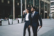 © BullRun - Successful diverse traders walking on modern city streets on way for meeting with business partners, elegant woman drinking caffeine beverage while strolling with colleague to office building