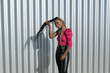 © NomadCam - Afro-style black girl with long black and blondes braids takes her hair with her hand and laughs with a metallic fence in the background