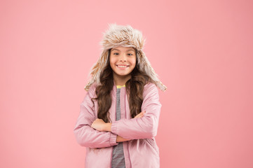 faux fur trend. playful kid girl wear fur hat with ear flaps pink background. soft furry accessory. 