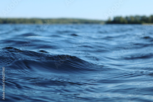 Blue water clear sky sunny day on finnish lake water waves close up. Beauty o...