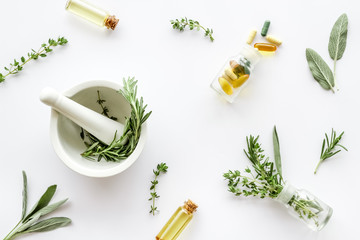 Medicine made from wildflowers and herbs with essential oils -pattern with mortar and pestle on white background top view