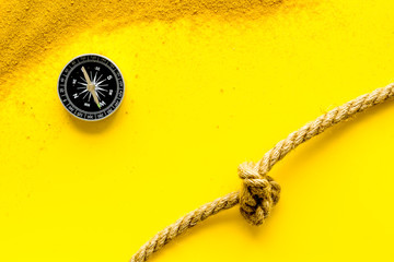 Wall Mural - Goal achievement concept. Compass near rope with knot on yellow background top view copy space
