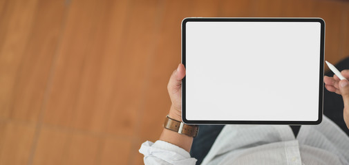 Wall Mural - Close-up view of young man using blank screen digital tablet while sitting in his office room