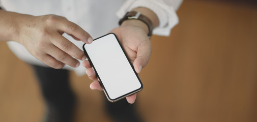 Wall Mural - Close-up view of man using blank screen smartphone while standing in his office room