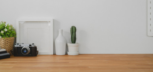 Cropped shot of comfortable office room with mock up frame, decorations and copy space on wooden table and white wall