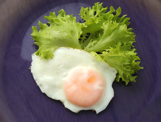 Wall Mural - fried eggs with green leaves of fresh lettuce on a purple background