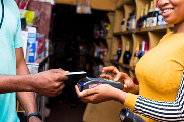 Wall Mural - contactless payment with a credit card and a mobile point of sale system in a local african retail store