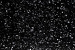 Leinwandbild Motiv Falling  snow at night. Bokeh lights on black background, flying snowflakes in the air. Overlay texture. Snowstorm