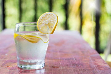 A glass of lemonade and cut lemon on a red table