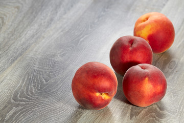 Wall Mural - Four ripe peaches lie on the wood table. Natural fruit.