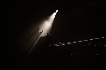 Canvas Print - Gray scale shot of a person standing on the stage under the spotlight