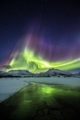 Wall Mural - Vertical shot of the reflection of the colorful northern lights in the half frozen lake