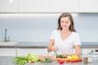 © Ermolaev Alexandr - Smiling young woman cooking in the kitchen at home. Empty space for text