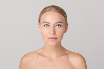 Portrait of beautiful young blonde with natural makeup looking aside and posing on white isolated background. Naked female model without accessories in studio. Concept of beauty and tenderness.