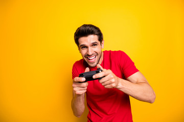 Portrait of cheerful guy play video games use joy stick want win winner in speed race wear stylish clothing isolated over yellow color background