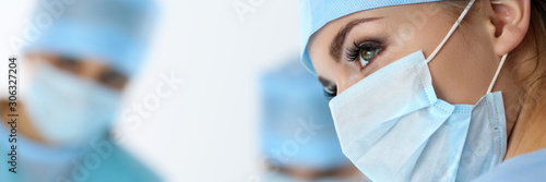Fototapeta na szkło Three surgeons at work operating in surgical theatre saving patient
