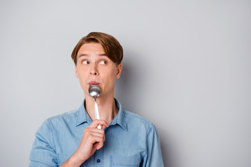 Diner time concept. Funky guy starving wait meal think thoughts what yummy supper his mother prepare lick spoon look copyspace wear stylish clothes isolated grey color background