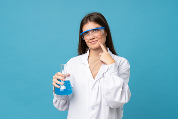 Young woman over isolated blue background with a scientific test tube