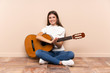 © luismolinero - Young woman with guitar sitting on the floor applauding