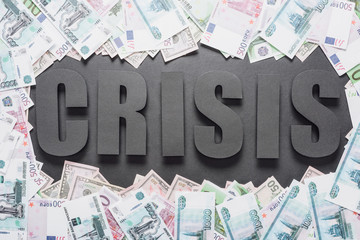 Wall Mural - top view of word crisis in frame of dollar and euro banknotes on black background with shadows