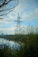 The Calm Morning Autumn Landscape With Fog And Beautiful Cloudy Sky Over The Pond With The Electricity Towers In The Background And Green Bushes In The Foreground