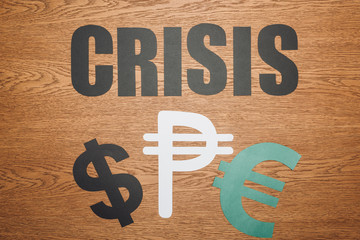 Wall Mural - top view of dollar, peso and euro paper cut symbols, and word crisis on wooden desk