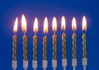 Burning golden birthday candles on blue background