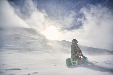 Wall Mural - Snowboarder on snowy day at winter mountains .