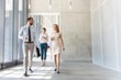 © MDBPIXS - Business professionals talking while walking in office corridor