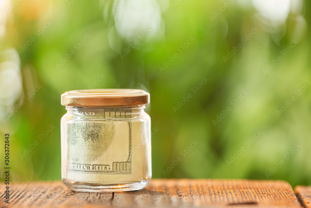 Jar with dollar banknotes on table outdoors. Money savings concept