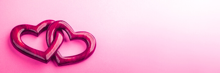 Wall Mural - banner of two pink wooden interlocking hearts with high gloss finish on pink background - valentine'