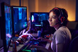 Teenage Girl Wearing Headset Gaming At Home Using Dual Computer Screens