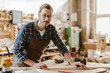 © LIGHTFIELD STUDIOS - selective focus of handsome carpenter in goggles standing near wooden plank on table
