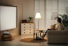 Young Woman Watching Movie Using Video Projector At Home