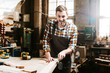 © LIGHTFIELD STUDIOS - selective focus of happy bearded carpenter carving wood in workshop