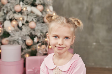 Cute little girl in pink dress with present on background Christmas tree. Merry Christmas and Happy Holidays! Baby healthy and winter concept. Family christmas.