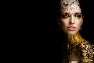 Beautiful woman portrait with golden glitter on her face. Girl with art make-up with golden sparkles. Fashion model with golden makeup